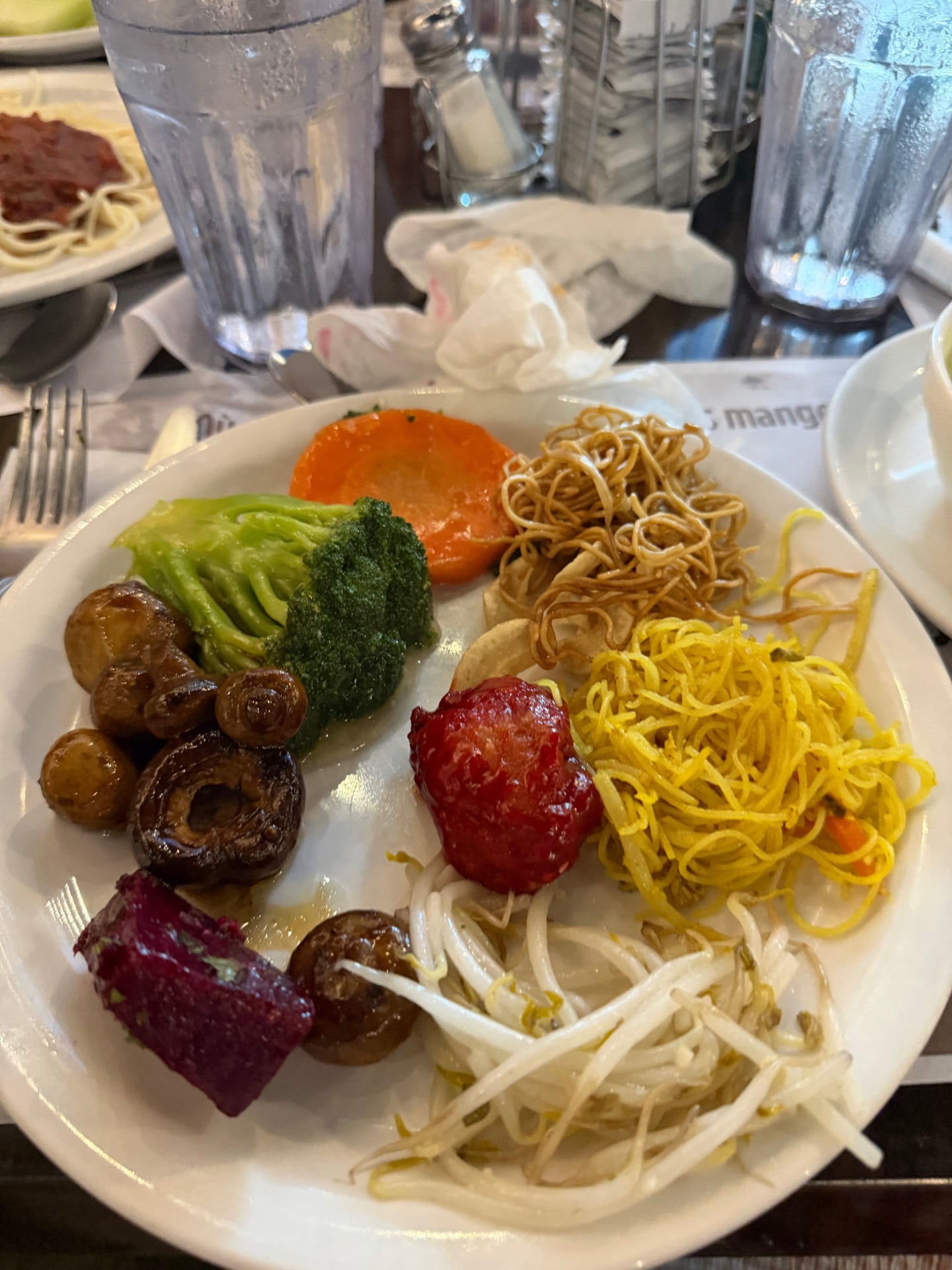 A buffet plate with vegetables, noodles, and beet salad